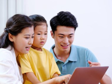 Üç kişilik mutlu aile dizüstü bilgisayar kullanıyor.