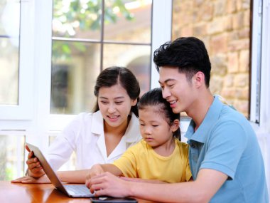 Üç kişilik mutlu aile dizüstü bilgisayar kullanıyor.