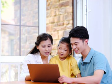 Üç kişilik mutlu aile dizüstü bilgisayar kullanıyor.