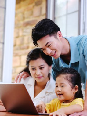 Üç kişilik mutlu aile dizüstü bilgisayar kullanıyor.