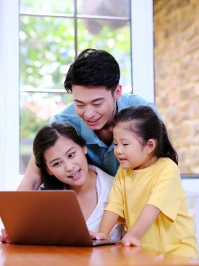 Üç kişilik mutlu aile dizüstü bilgisayar kullanıyor.