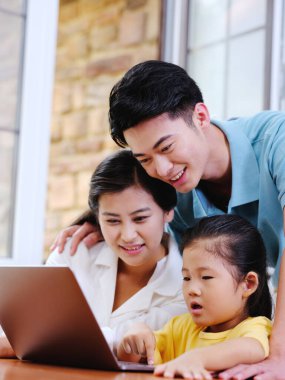 Üç kişilik mutlu aile dizüstü bilgisayar kullanıyor.