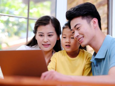 Üç kişilik mutlu aile dizüstü bilgisayar kullanıyor.