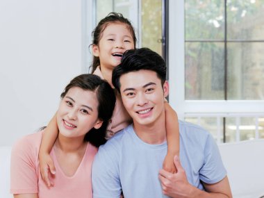 Üç kişilik mutlu bir aile oturma odasındaki kanepede oturuyor.