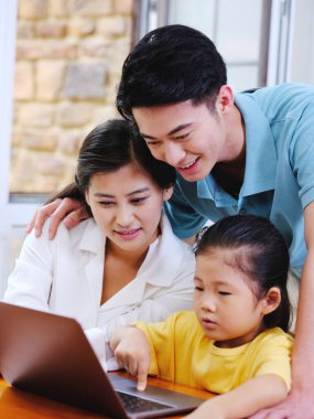 Üç kişilik mutlu aile dizüstü bilgisayar kullanıyor.