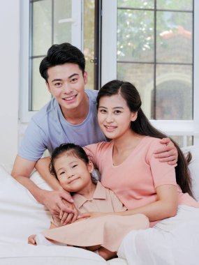 Üç kişilik mutlu bir aile oturma odasındaki kanepede oturuyor.