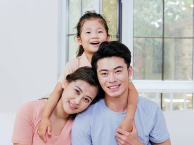 Üç kişilik mutlu bir aile oturma odasındaki kanepede oturuyor.