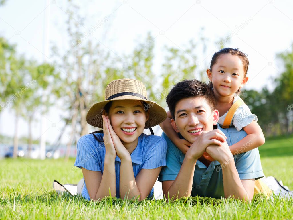 Happy family of three lying on the grass