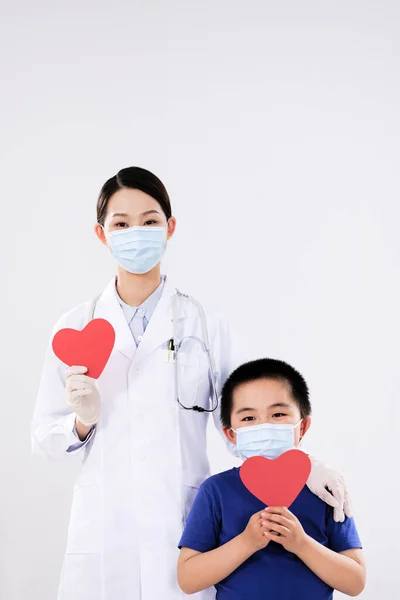 Een vrouwelijke dokter en een kleine jongen hadden elk een rood hart. — Stockfoto