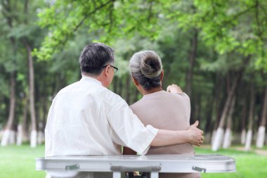 Parktaki sandalyelerde oturan mutlu yaşlı çift