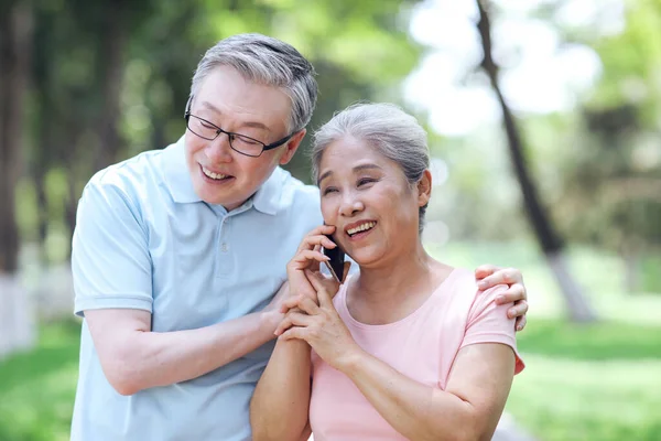 Heureux les vieux couples utilisent les téléphones mobiles pour passer des appels à l'extérieur — Photo