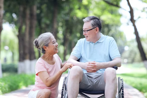 De oude man duwt zijn vrouw in een rolstoel — Stockfoto