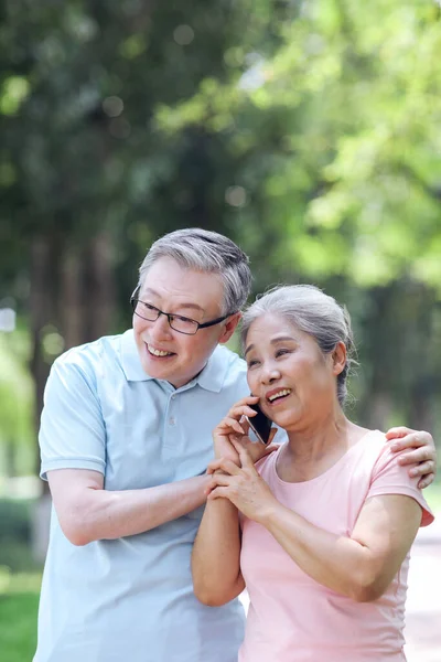 Felice vecchie coppie utilizzano i telefoni cellulari per effettuare chiamate all'aperto — Foto Stock