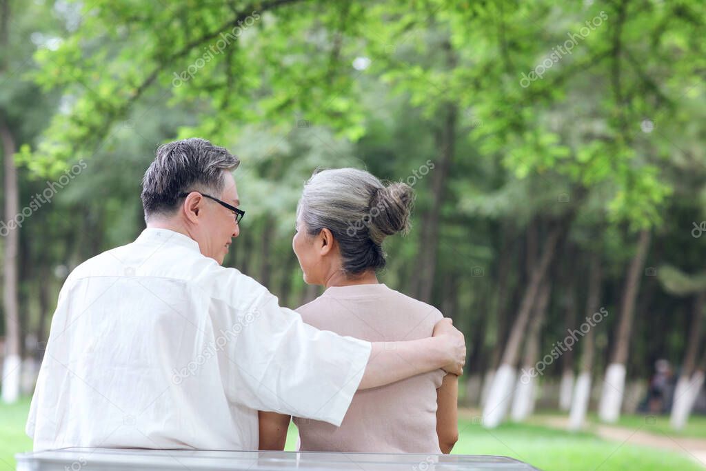 Happy old couple sitting on chairs in outdoor park