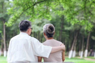 Parktaki sandalyelerde oturan mutlu yaşlı çift