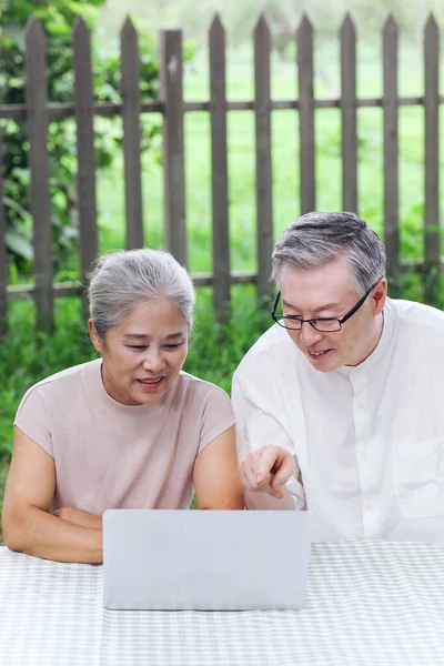 Happy old couple use computer to surf the Internet outdoors — Stock Photo, Image