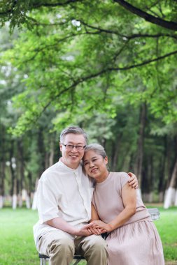 Parktaki sandalyelerde oturan mutlu yaşlı çift