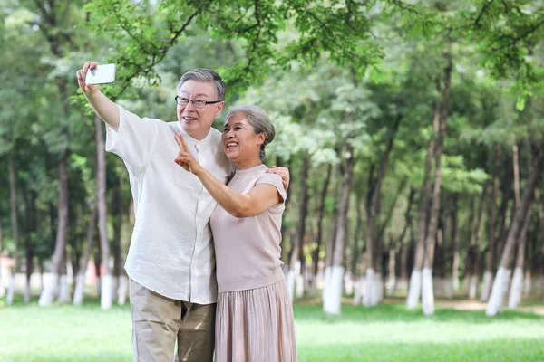 Glada gamla par ta selfie med mobiltelefon i parken — Stockfoto