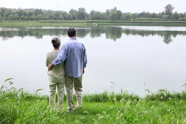 Casal velho feliz assistindo a paisagem junto ao lago — Fotografia de Stock