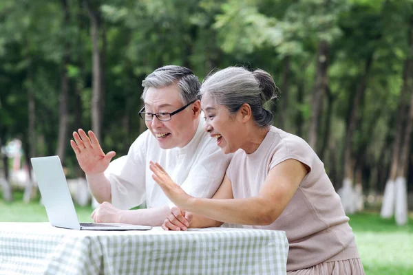 Elderly couples use computer video chat outdoors — Stock Photo, Image