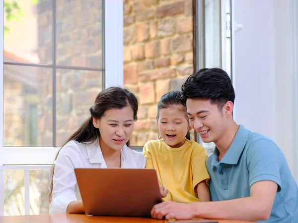 Una familia feliz de tres usando el ordenador portátil — Foto de Stock