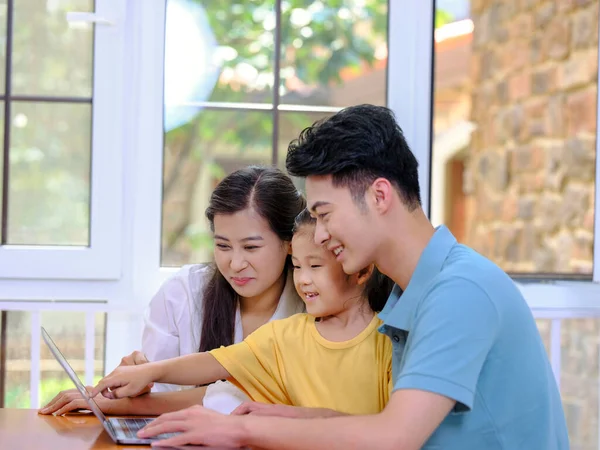 En lycklig familj på tre med bärbar dator — Stockfoto
