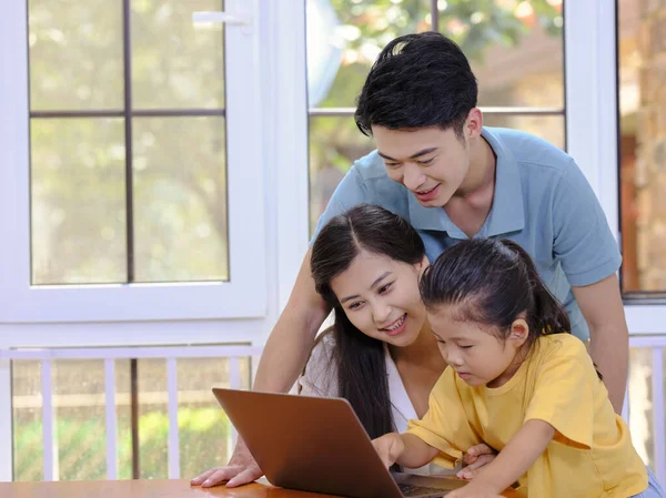 Uma família feliz de três usando laptop — Fotografia de Stock