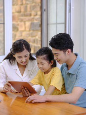 Üç kişilik mutlu bir aile tablet kullanıyor.