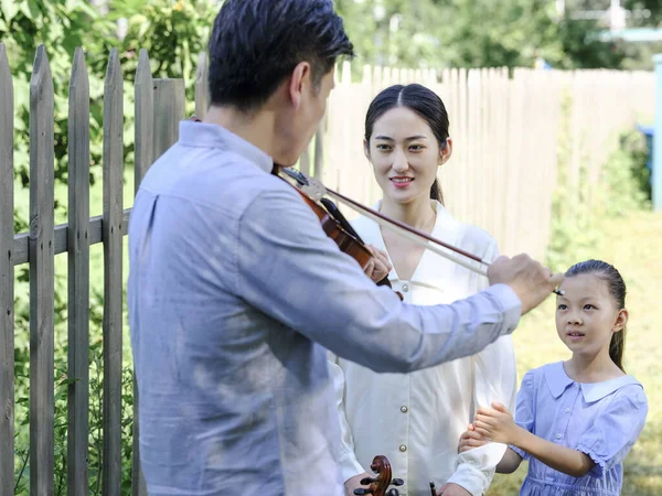 Famiglia felice di tre che suonano il violino nel parco — Foto Stock