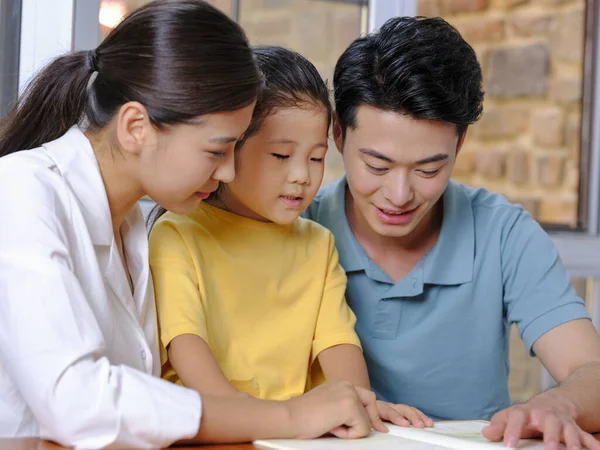 Eine glückliche dreiköpfige Familie liest zusammen — Stockfoto