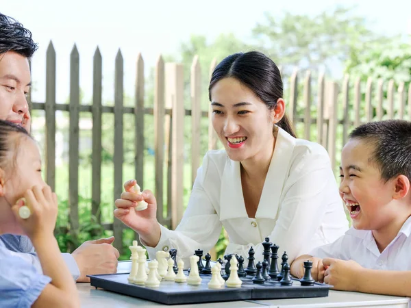 Família feliz de quatro jogando xadrez no parque — Fotografia de Stock