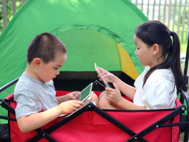 Tabletlerle bilgisayar oynayan iki mutlu çocuk.