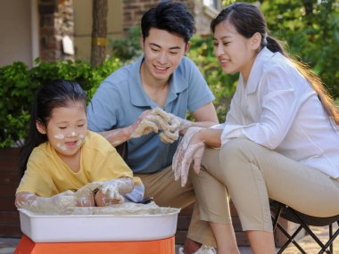 Üç kişilik mutlu aile dışarıda çömlekçilik yapıyor.