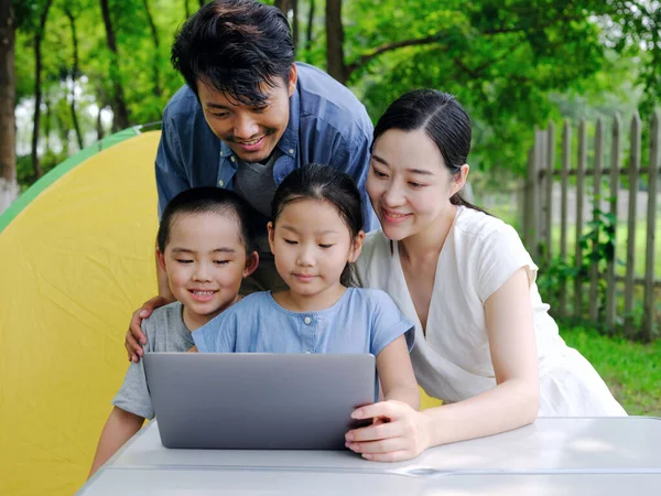 Boldog család négy használja számítógép szörfözni az interneten a szabadban — Stock Fotó