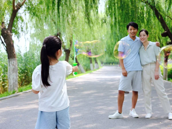 Una familia feliz de tres está jugando en el parque —  Fotos de Stock