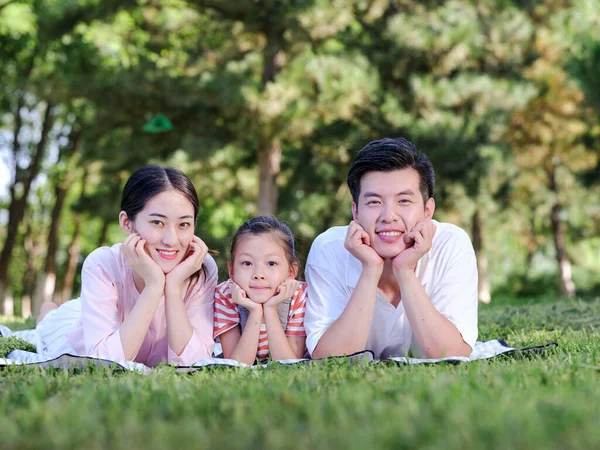 Família feliz de três na grama do parque — Fotografia de Stock