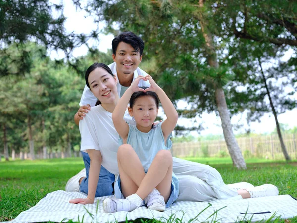 Família feliz de três brincando no parque — Fotografia de Stock