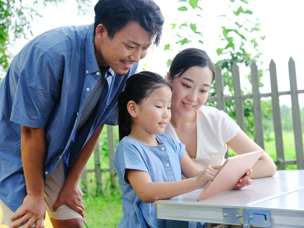 Família feliz de três usos tablet computador ao ar livre — Fotografia de Stock