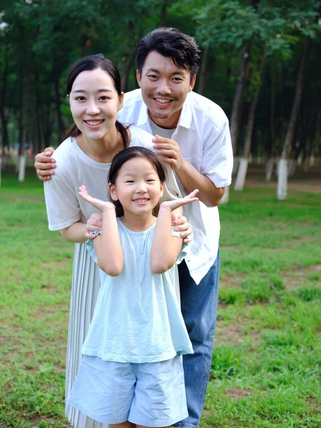 Família feliz de três brincando no parque — Fotografia de Stock