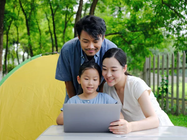 Familia feliz de tres utilizan la computadora para navegar por Internet al aire libre — Foto de Stock
