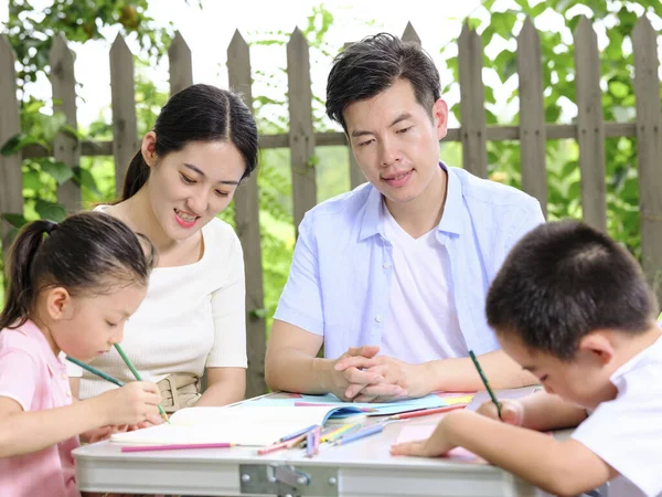 Young parents help their children with their homework outdoors — Stock Photo, Image