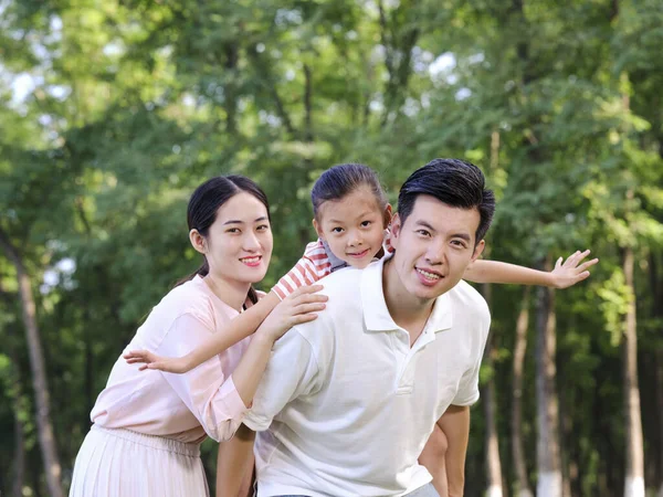 Família feliz de três brincando no parque — Fotografia de Stock