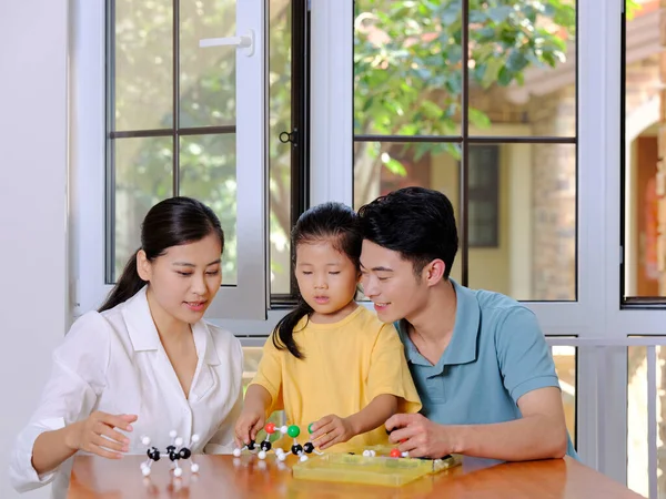 Glückliche dreiköpfige Familie macht gemeinsam Molekularstrukturmodell — Stockfoto