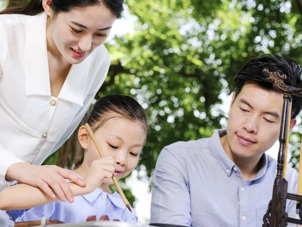 Happy family of three writing calligraphy outdoors — Stock Photo, Image