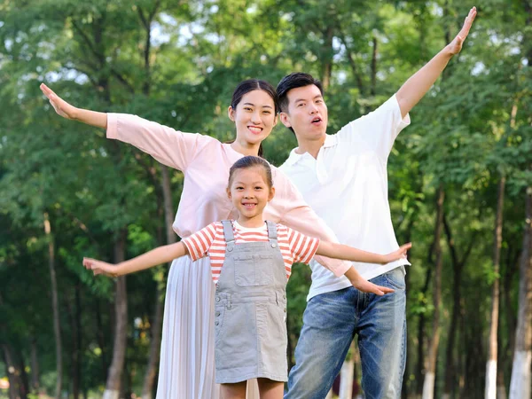 Família feliz de três brincando no parque — Fotografia de Stock