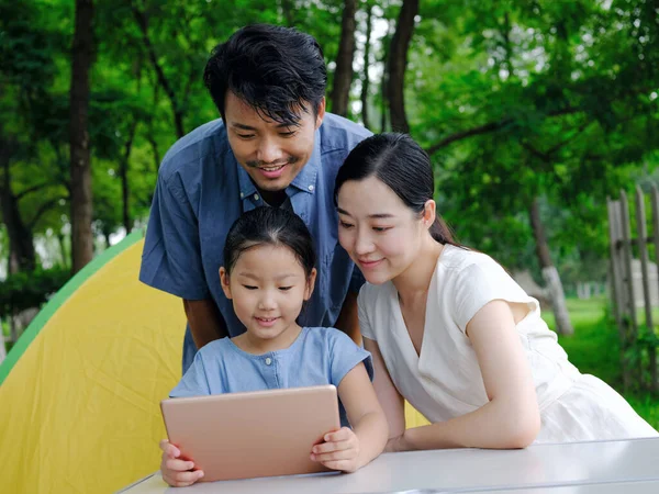 Happy family of three uses tablet computer outdoors — Stock Photo, Image