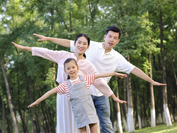 Família feliz de três brincando no parque — Fotografia de Stock