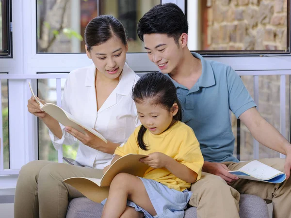 En lycklig familj på tre personer läser på soffan — Stockfoto