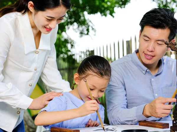 Glückliche dreiköpfige Familie schreibt Kalligraphie im Freien — Stockfoto