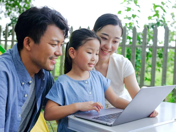 Happy family of three use computer to surf the Internet outdoors — Stock Photo, Image